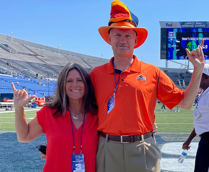 A woman and man stand beside each other hugging with their hands up signaling a "Birds Up."