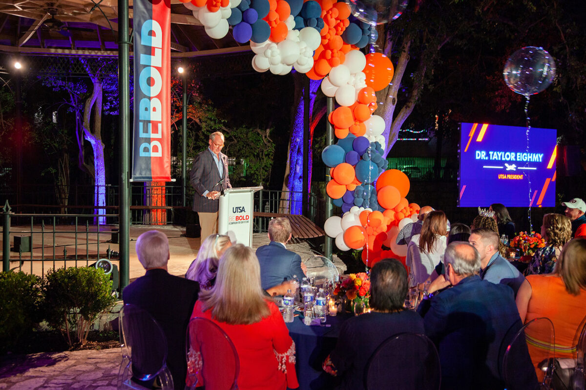 A man stands at a podium at an event in the evening.