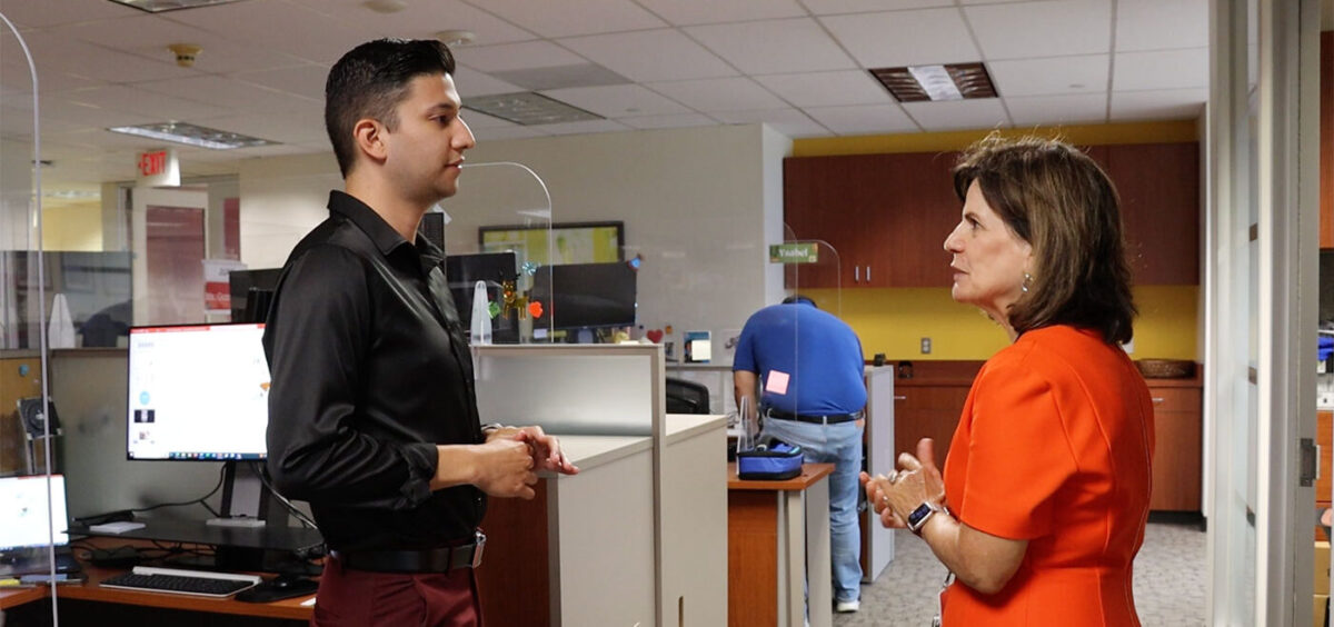 A man has a conversation with a woman in an orange dress.
