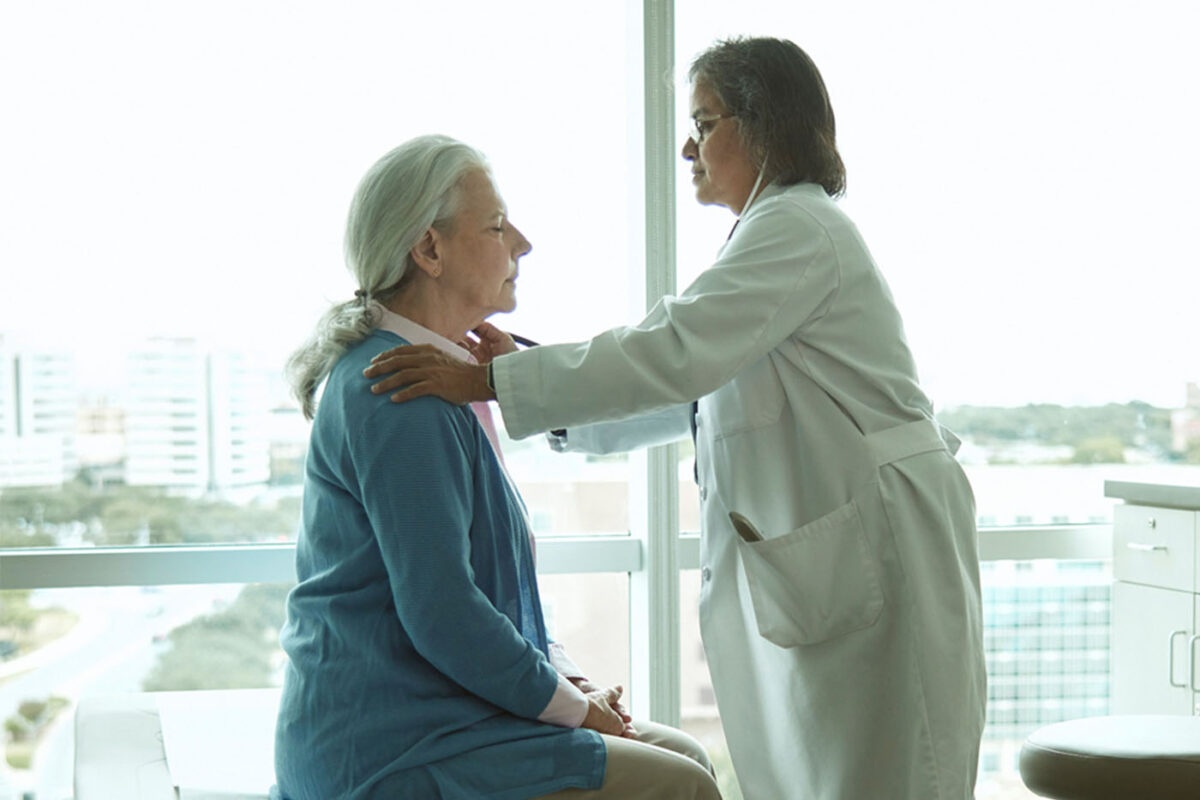 A female doctor at the Glenn Biggs Institute examines the neck and head of a female patient