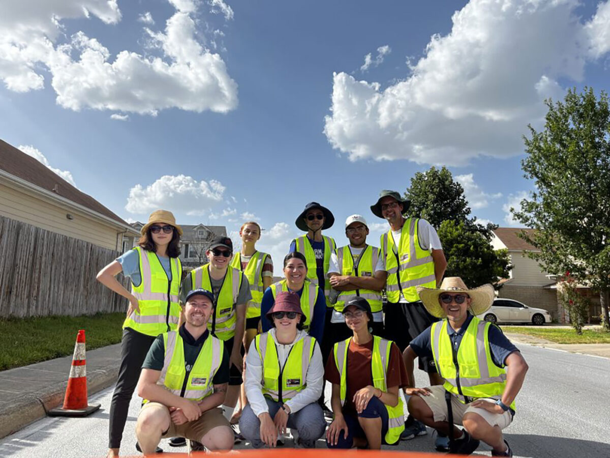 A group people in yellow safety vests huddle together for a group photo.