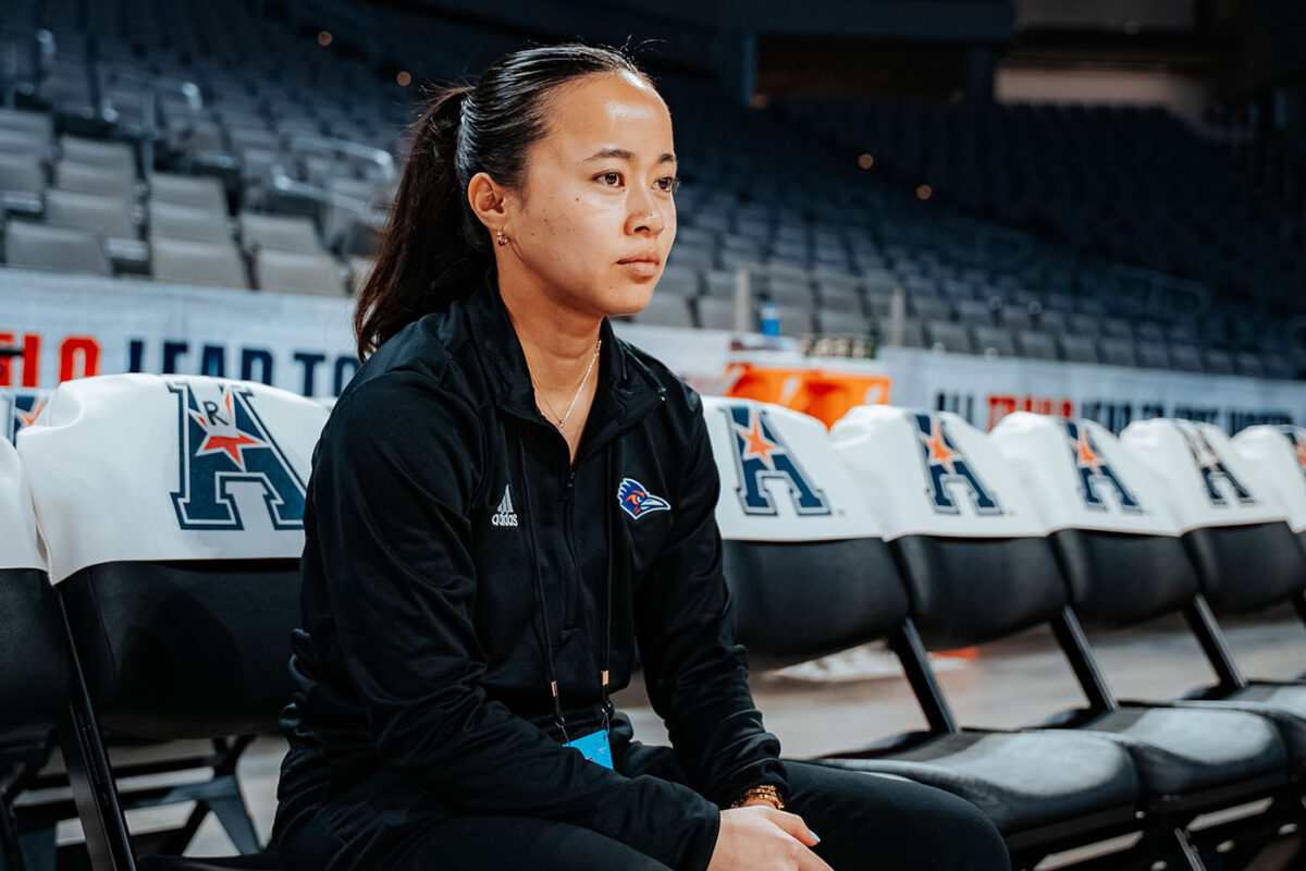 Assistant athletic trainer Tam Nguyen sits on a chair on the sideline.