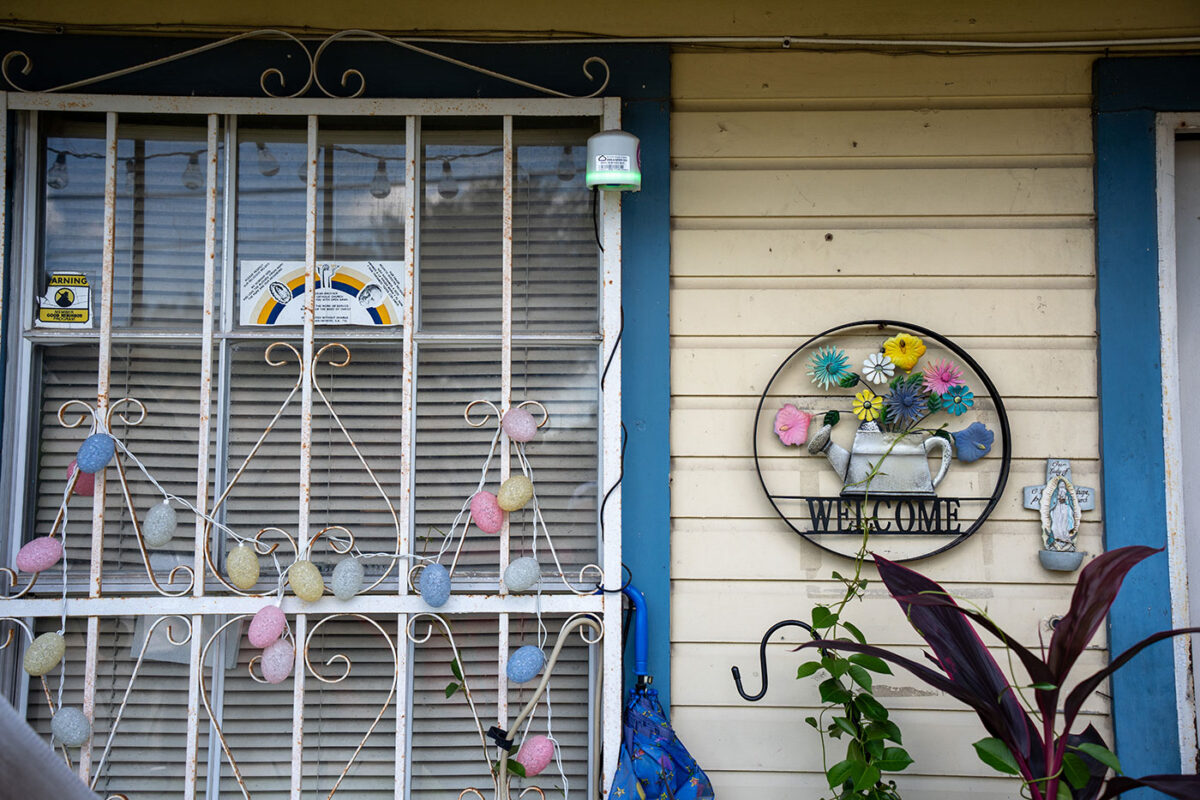 A photo of a exterior window and an iron welcome sign beside it.