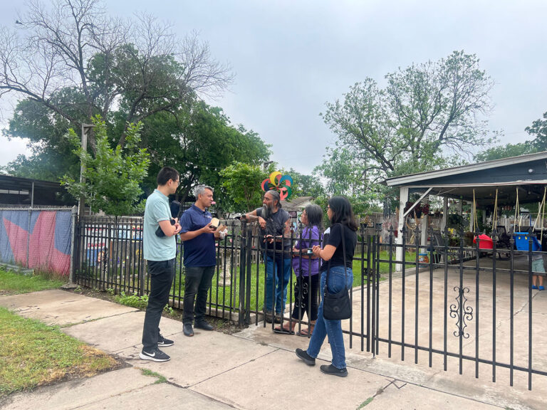 Five people stand at a iron gate to talk to each other.