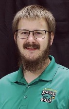 A man in a green polo and glasses smiles at the camera.