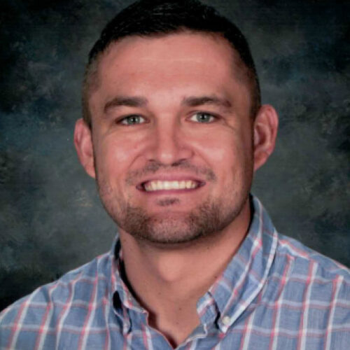 A man in a plaid shirt smiling at the camera.