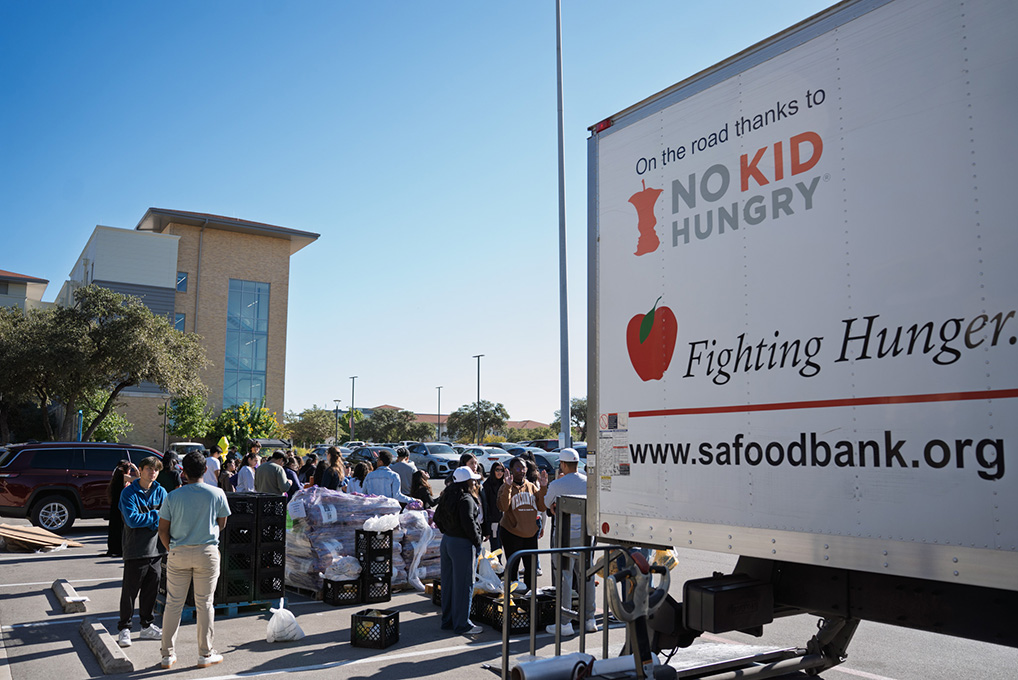 A box truck is parked to the right as people line up down below it to unload the contents from the truck.