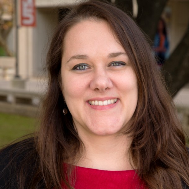 A headshot of a woman in a red shirt and black blazer.