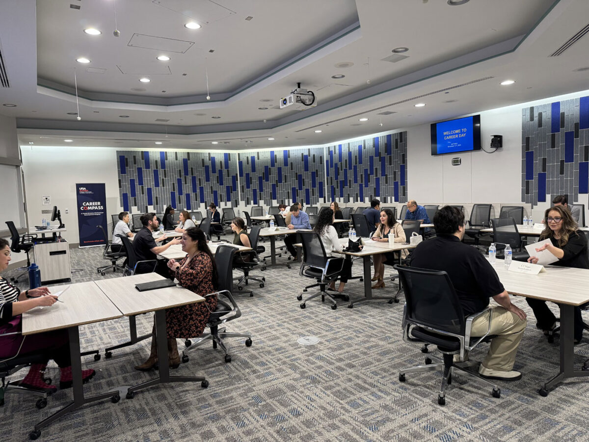 An event meeting space is filled with several individuals at large tables speaking.