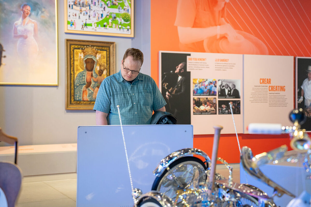 A man in a blue shirt and glasses looks down at an interactive screen at the Institute of Texan Cultures.