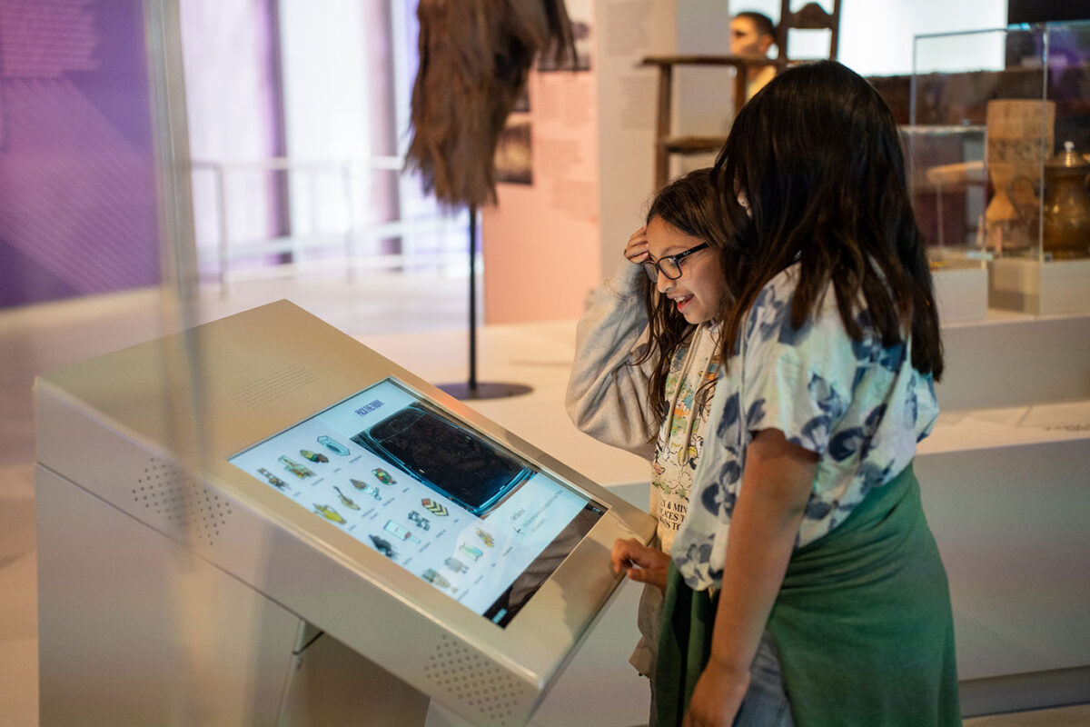 Two young girls stand in front of a digital screen as they interact with an exhibit at the Institute of Texan Cultures.