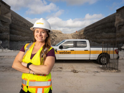 Bonnie Lee poses in front of a Webber pickup truck at a freeway construction site