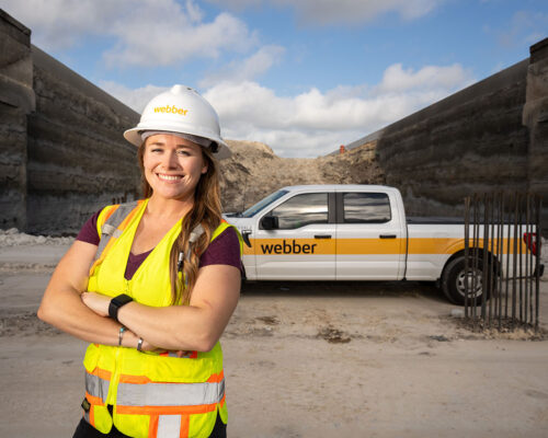 Bonnie Lee poses in front of a Webber pickup truck at a freeway construction site