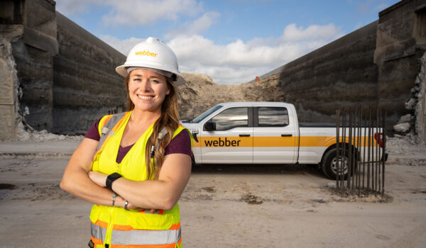 Bonnie Lee poses in front of a Webber pickup truck at a freeway construction site