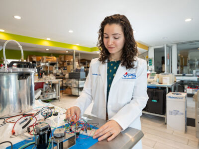 Isabella Cano adjusts electrical wires hooked to a device in a laboratory