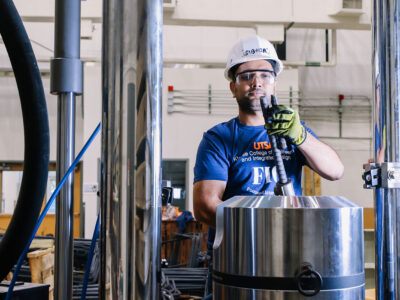 A construction science and management student works on a task with rebar