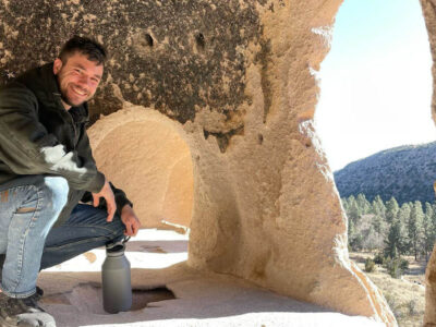 James MIsutka kneels dove in a cave.
