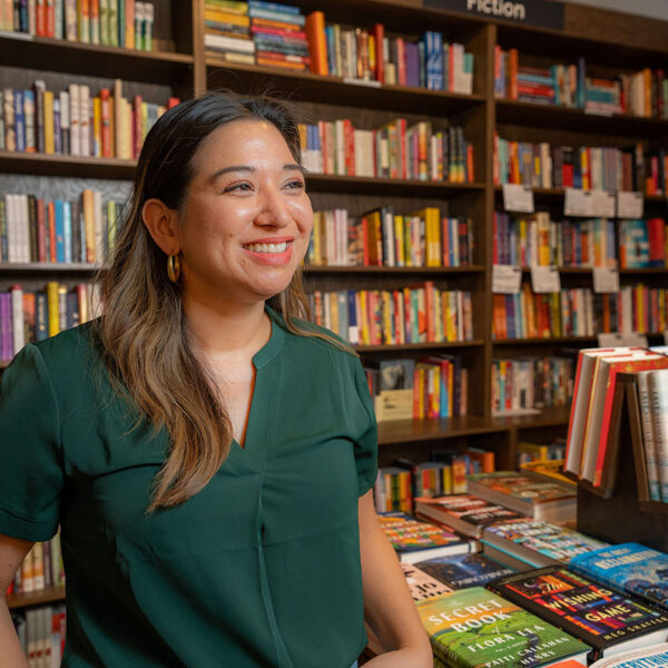 Kimberly Garza smiles while standing in front of bookshelves.