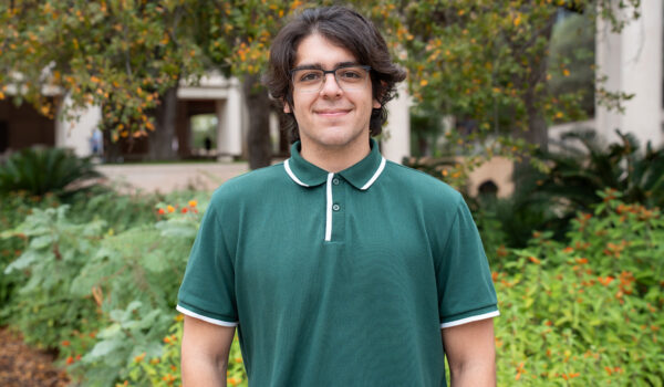 A man in a green polo shirt smiles at the camera.