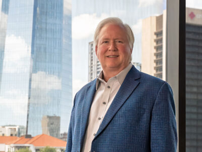 Man in blue suit with a city scape behind him.