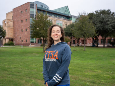 A woman stands in front of a building.