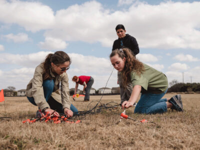 UTSA students lay down instruments for seismic surveying in a field at the Park West Campus.