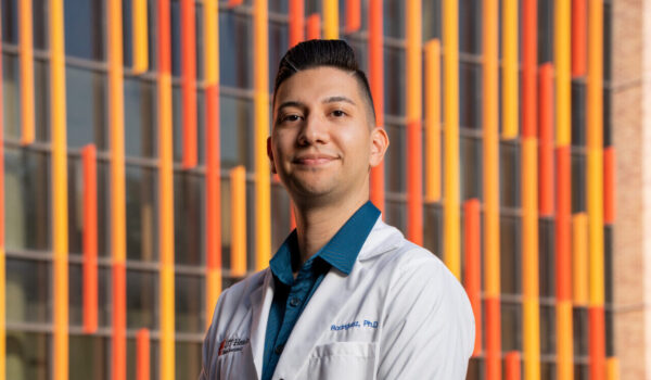 A man in a white lab coat smiles.