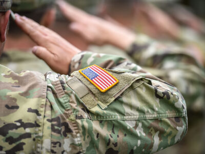 A row of service people with their arms up to their face for a salute.