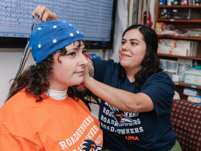 A UTSA researcher adjusts an EEG cap atop a subject's head