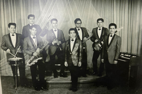 Sunny & The Sunliners stand together on stage side by side.