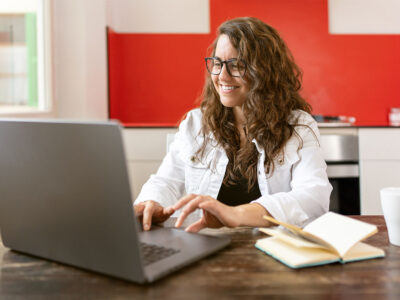 A woman types on a laptop in her kitchen