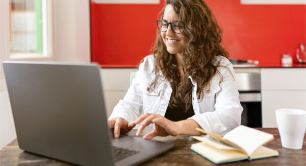 A woman types on a laptop in her kitchen